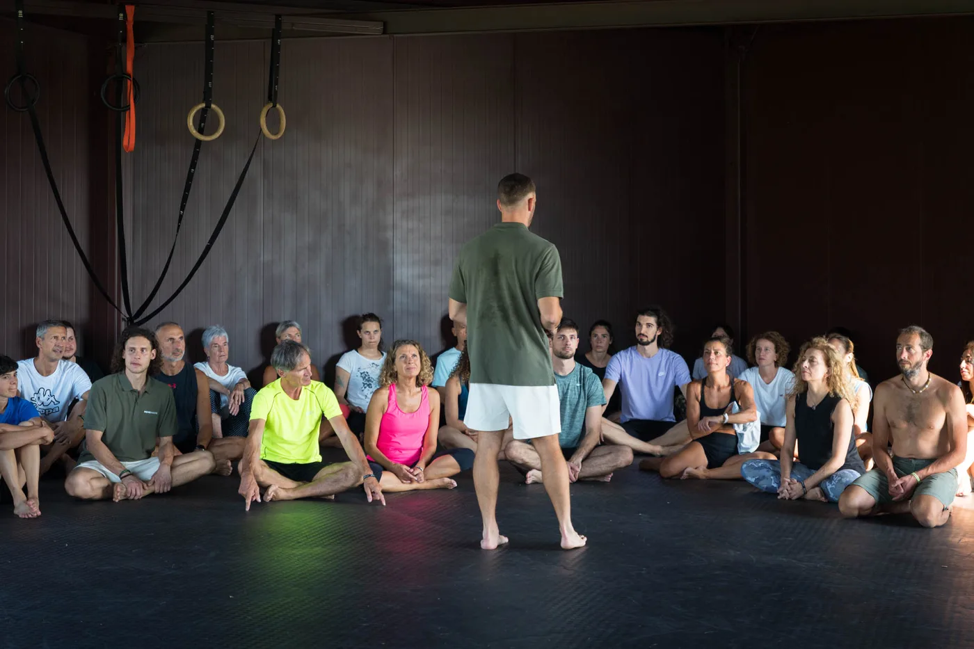 Interno di uno studio di allenamento con anelli e gruppo di allievi seduti a lezione