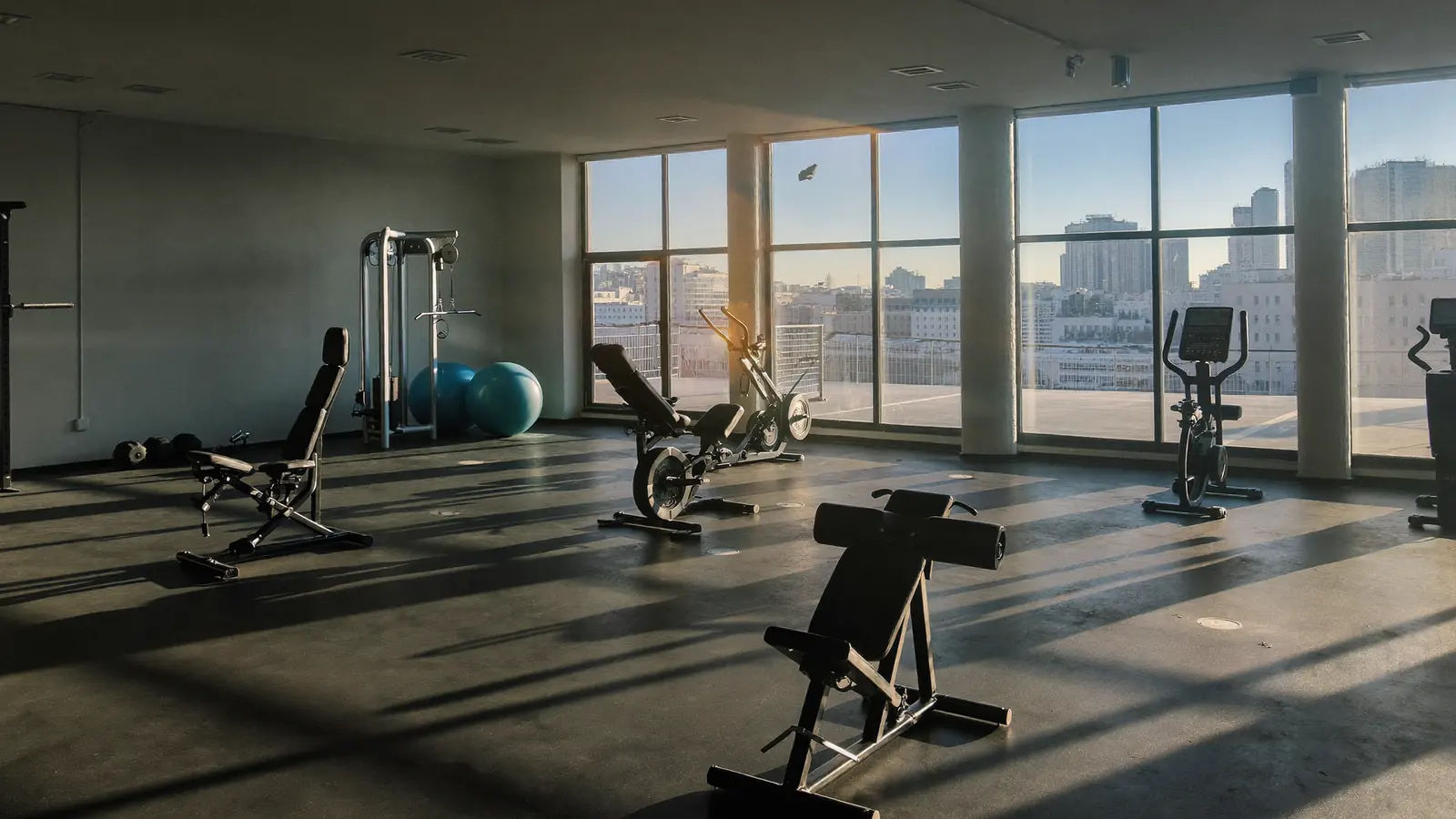 Sala di una palestra vuota al mattino con gli attrezzi in ordine e luce dalle vetrate