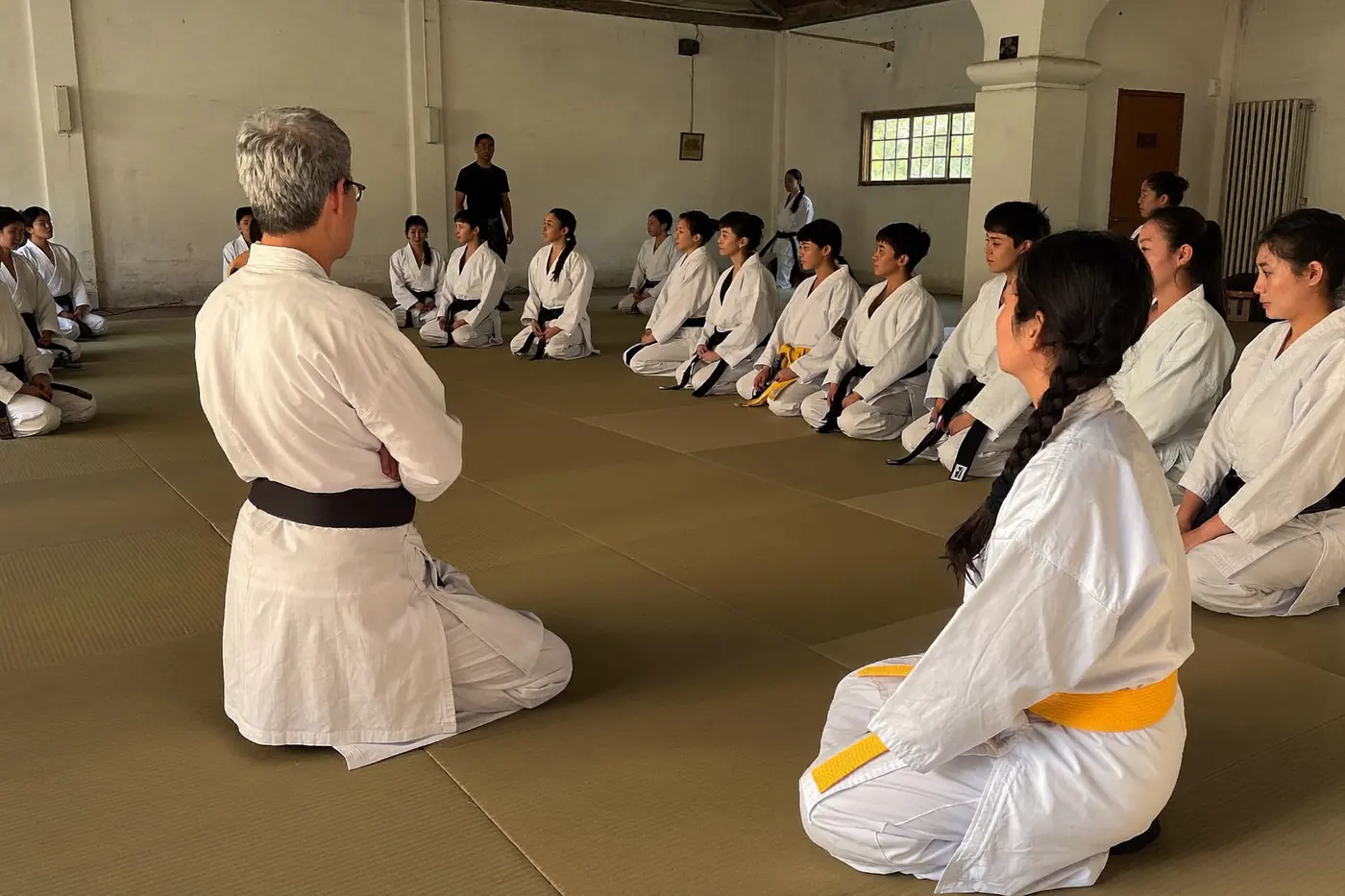Gruppo di praticanti seduti in seiza sul tatami mentre ascoltano l'istruttore