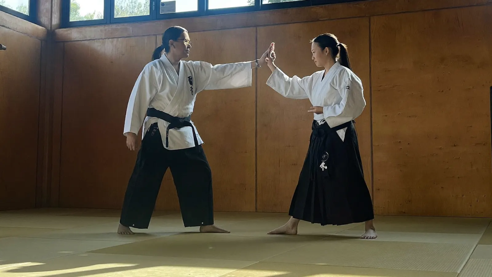 Istruttore in kimono che corregge la guardia di un allievo adulto sul tatami di un dojo