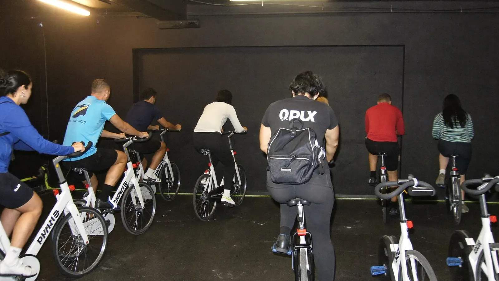 Sala di indoor cycling con file di spin bike e istruttore sulla bici davanti al gruppo