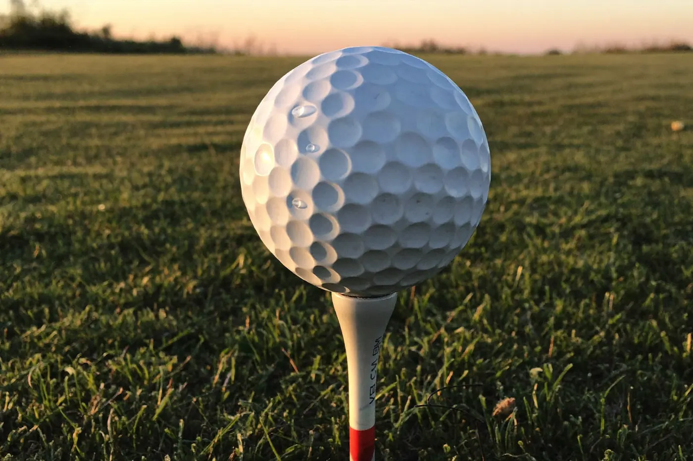Sacca da golf con alcuni ferri e palline su un tappetino del campo pratica, primo piano