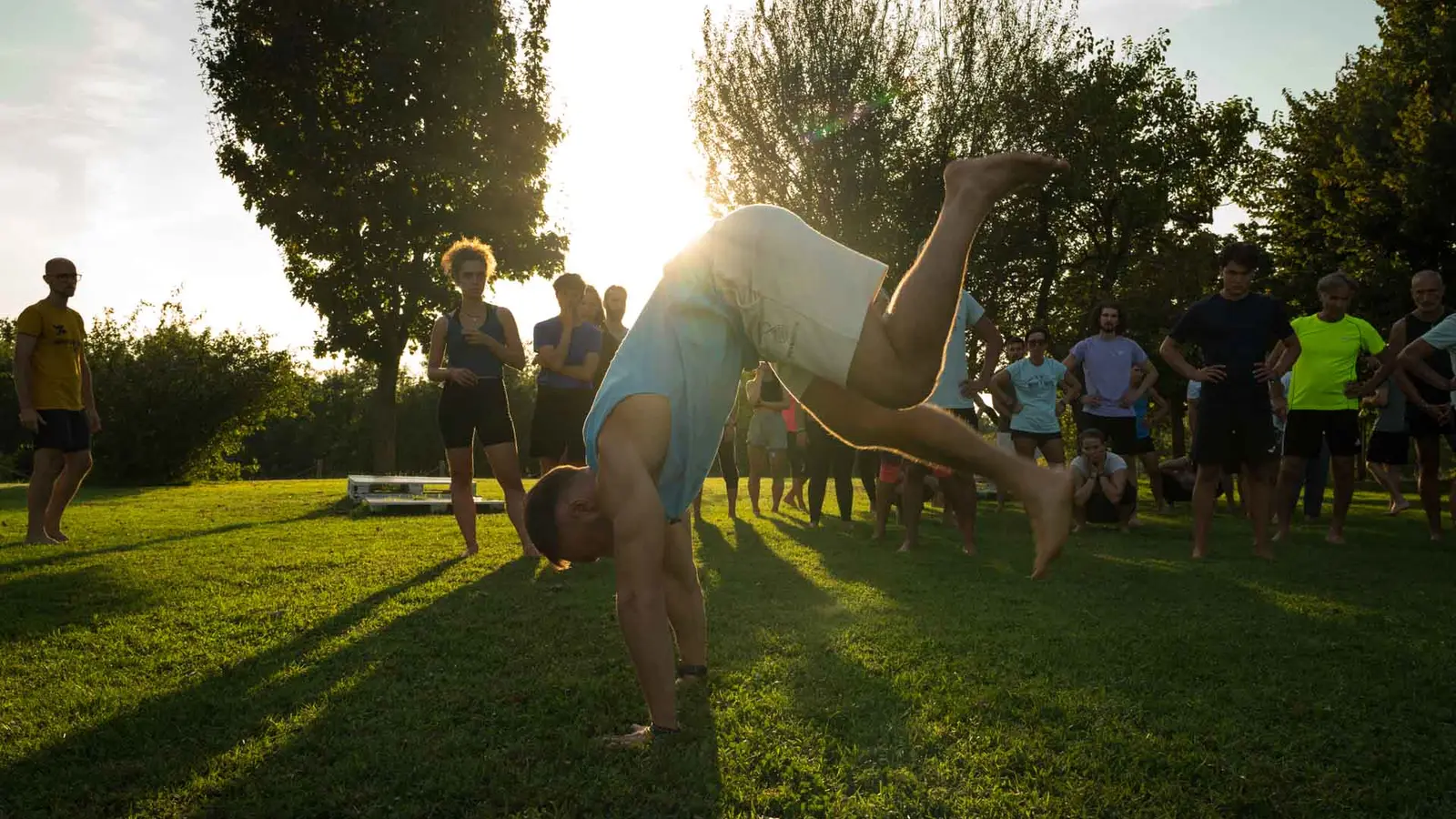 Un allievo esegue un movimento acrobatico all'aperto durante un intensivo Moveinside, con il gruppo che osserva