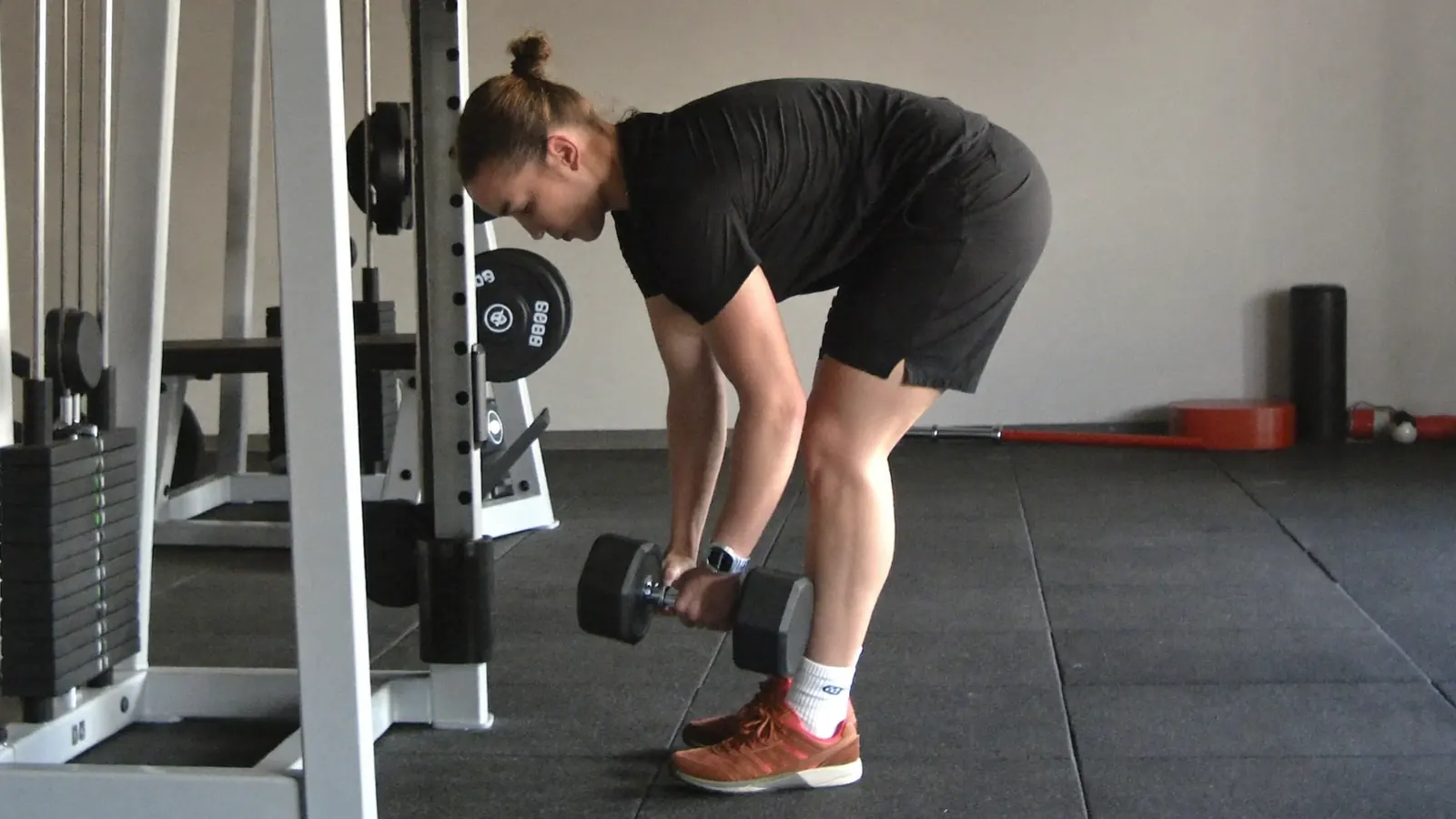 Persona che si allena in palestra affiancata da un istruttore, nelle ore serali