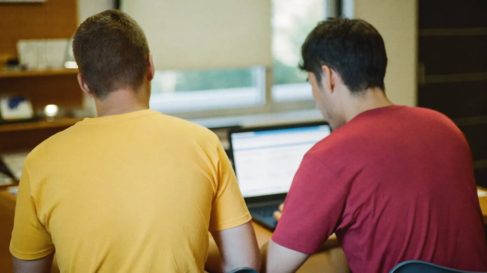 Due persone di spalle davanti a un computer portatile nell'ufficio di una piccola società sportiva