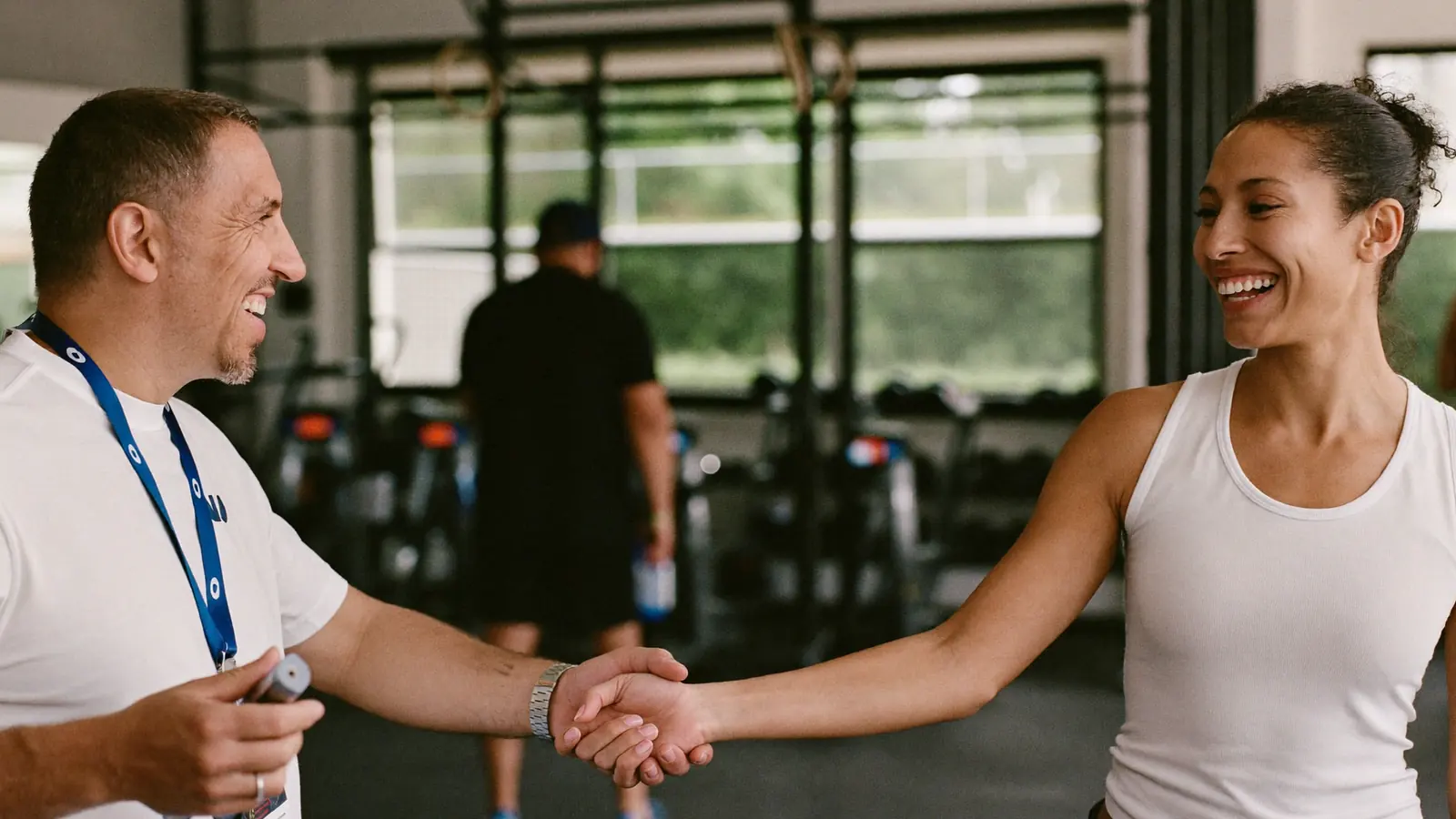 Personal trainer accoglie una nuova cliente con una stretta di mano in palestra